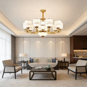 May include: A modern living room featuring a large, ornate chandelier with multiple white and gold light fixtures. The room includes a beige sofa, two armchairs, a coffee table, and two side tables with lamps. The overall design is elegant and contemporary.