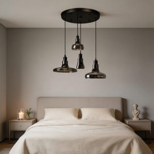 May include: A modern black pendant light fixture with four individual lights hanging from a circular ceiling mount. The lights have a dark gray glass shade and are suspended above a bed with a neutral-colored comforter.