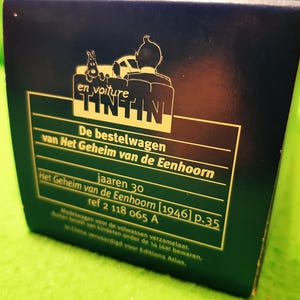 以下が含まれることがあります： ティンティンのロゴとオランダ語のテキストが特徴の濃い青色の箱。 箱には車に乗ったタンタンのイラストが含まれています。 テキストは「De bestelwagen van Het Geheim van de Eenhoorn」と「jaaren 30」と書かれています。