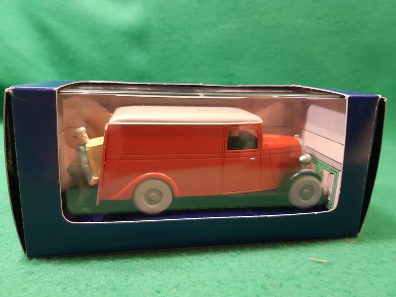 以下が含まれることがあります： 主に赤色でクリーム色の屋根のヴィンテージ配送バンのダイキャストモデル。バンはグレーのホイールで、青い箱に入っています。箱を運んでいる男性の小さなフィギュアが含まれています。