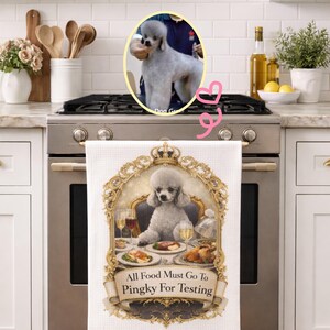 May include: White kitchen towel featuring a regal poodle illustration seated at a table laden with food and drinks. The towel has a decorative gold frame and the text "All Food Must Go To Pingky For Testing". A photo of a poodle is in the background.