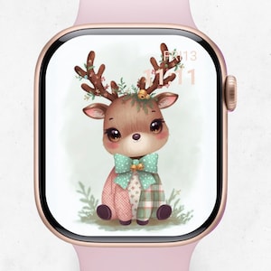 以下が含まれることがあります： ローズゴールドのスマートウォッチは、気まぐれな鹿のイラストを表示します。鹿は、緑で飾られた茶色の角、ミントグリーンのリボン、ピンクと緑のパッチワークの体を持っています。時計の文字盤には日付も表示されます。
