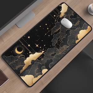 May include: A rectangular desk mat featuring a black background with a celestial design of gold-coloured clouds, a crescent moon, and scattered stars. The mat has a white computer mouse placed on its surface, which is positioned on a wooden desk.