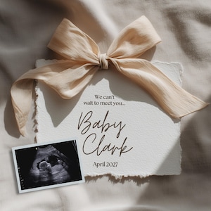 Puede incluir: Una tarjeta de anuncio de embarazo con un lazo color crema y el texto "We can't wait to meet you... Baby Clark April 2027." También se incluye una imagen de ultrasonido.