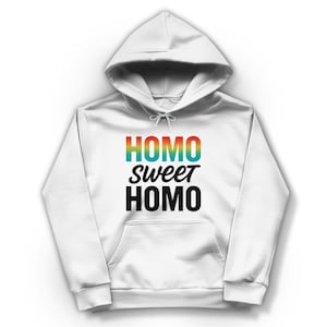 Könnte beinhalten: Ein weißer Kapuzenpullover mit einer Vordertasche und einem Kordelzug. Auf der Vorderseite des Sweatshirts steht der Text "HOMO sweet HOMO" in Regenbogen- und schwarzer Schrift.