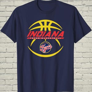 May include: A navy blue short-sleeve t-shirt featuring a large yellow basketball graphic. The text INDIANA FEVER BASKETBALL is printed in red across the center, with the Indiana Fever team logo positioned below the text in red, blue, and yellow.