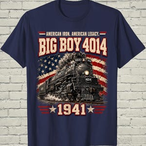 May include: A navy blue t-shirt featuring a graphic of a black steam locomotive labeled 4014. The design includes the text AMERICAN IRON. AMERICAN LEGACY. BIG BOY 4014 and 1941, set against a distressed American flag background with red and white stripes.