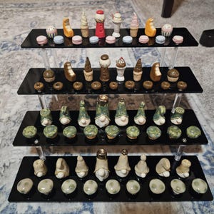 May include: A tiered display of miniature ceramic sculptures. The top tier features ice cream cones, a gumball machine, and macarons. The middle tier displays ice cream cones and donuts. The bottom tier showcases gnomes and mushroom-shaped objects. The sculptures are in various colors.