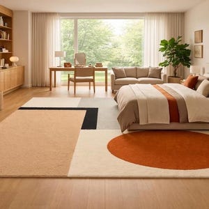 May include: A large rectangular area rug featuring a geometric design with a prominent burnt orange circle, a large beige block, and smaller black and gray rectangular accents on a cream-colored background, crafted with a soft, textured pile finish.