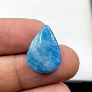 May include: A teardrop-shaped cabochon gemstone featuring a vibrant sky-blue color with intricate white marbling patterns throughout the surface. The stone has a smooth, polished finish and a rounded base that tapers to a point at the top.