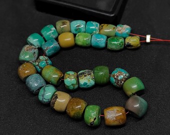 May include: A strand of irregular, barrel-shaped turquoise beads in various shades of blue, green, and brown. The beads feature natural matrix patterns and are strung on a thin red cord, showcasing a mix of polished and matte surface textures.