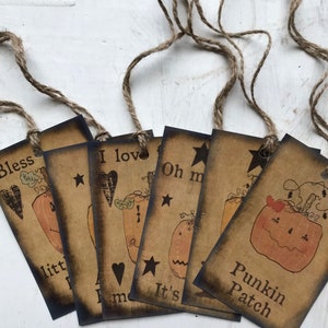 May include: A collection of rustic-style gift tags with brown cardstock and jute twine. Each tag features a pumpkin illustration and text, including "Bless," "I love," "Oh my," and "Punkin Patch." The tags have a distressed, vintage aesthetic.