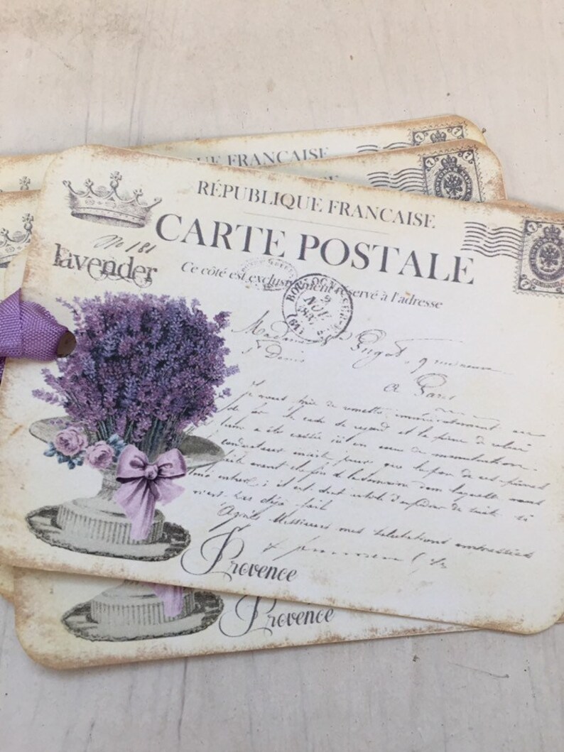May include: A vintage postcard with a lavender bouquet in a hat, featuring the text "No 181 Lavender" and "Carte Postale" in French. The postcard has a worn, aged look and is printed on thick paper.