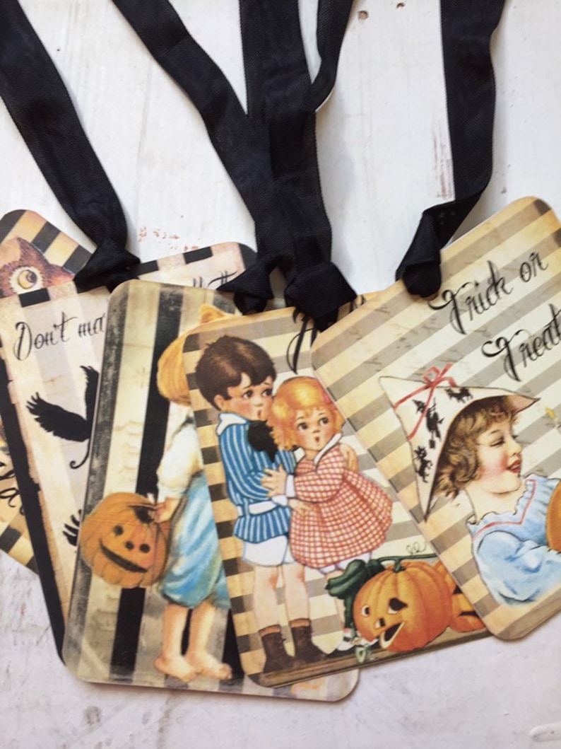 May include: Four rectangular paper tags with black ribbon loops, featuring vintage-style illustrations of children in costumes, pumpkins, and black stripes. One tag displays the text "Trick or Treat" and another shows "Don't make".