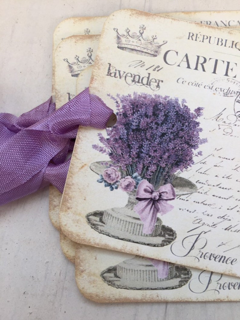 May include: A stack of vintage-style gift tags with a lavender theme. The tags feature a crown, the words "N&deg;181 lavender", and a bouquet of lavender flowers in a hat. The text "REPUBLIC FRANCAISE CARTE Ce c&ocirc;t&eacute; est exclusif" is also visible.
