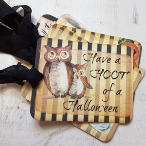 May include: A set of rectangular paper tags featuring a brown and black vertical striped background. Each tag displays an illustration of two brown owls and the black text "Have a HOOT of a Halloween". A black ribbon is threaded through a hole.