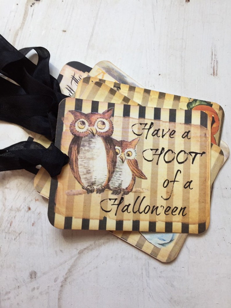 May include: A set of rectangular paper tags featuring a brown and black vertical striped background. Each tag displays an illustration of two brown owls and the black text "Have a HOOT of a Halloween". A black ribbon is threaded through a hole.