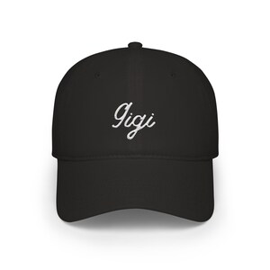 May include: Black baseball cap with a curved peak. The word "Gigi" is embroidered in white script across the front. The cap is made of a soft fabric and has a structured crown.