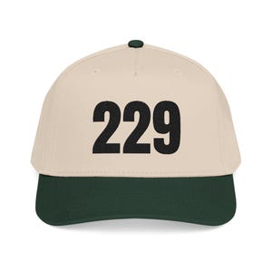 Könnte beinhalten: Baseballcap mit cremefarbener Krone und dunkelgrünem Schirm. Die Zahl "229" ist in fetter schwarzer Schrift auf der Vorderseite abgebildet. Die Kappe hat einen gebogenen Schirm und einen Knopf oben.