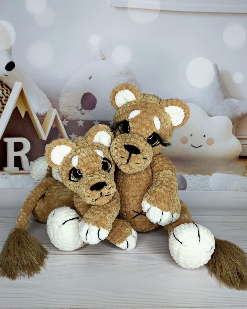 Puede incluir: Dos cachorros de le&oacute;n de peluche hechos a mano. Los leones son marrones con detalles blancos en las orejas, las patas y las caras. Tienen narices, pesta&ntilde;as y colas negras. Los cachorros est&aacute;n sentados juntos, creando una apariencia acogedora.