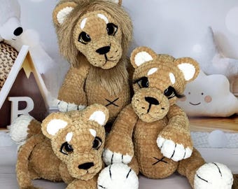 May include: Three handmade crochet lion stuffed animals. The lions are various sizes and have brown bodies, white paws, and white-tipped ears. The largest lion has a brown mane. Each lion has a black nose and eyes.