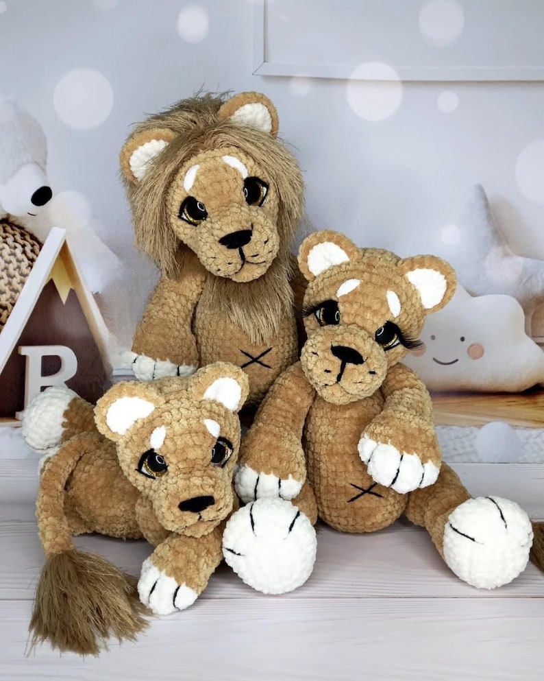 Puede incluir: Tres peluches de le&oacute;n de ganchillo hechos a mano. Los leones son de varios tama&ntilde;os y tienen cuerpos marrones, patas blancas y orejas con puntas blancas. El le&oacute;n m&aacute;s grande tiene una melena marr&oacute;n. Cada le&oacute;n tiene nariz y ojos negros.