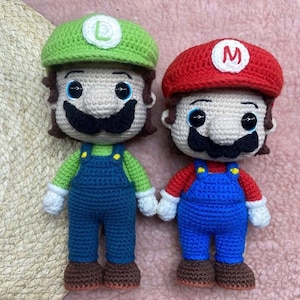 May include: Two crocheted dolls of video game characters, Mario and Luigi. Mario wears a red hat with a white "M", a red shirt, and blue overalls. Luigi wears a green hat with a white "L", a green shirt, and blue overalls. Both have black mustaches.