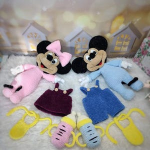 Puede incluir: Mu&ntilde;ecos de Mickey y Minnie Mouse tejidos a crochet con conjuntos y accesorios a juego. Los mu&ntilde;ecos visten peleles rosas y azules, petos morados y azules, baberos amarillos y biberones. La mu&ntilde;eca Minnie Mouse tiene un lazo rosa.