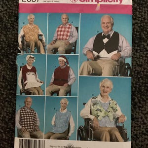 May include: A Simplicity sewing pattern envelope 2687 for one size adult bibs. The front cover features photographs of various bib styles including a tuxedo design, a Santa suit, a butterfly print, and plaid patterns, all worn by adults.