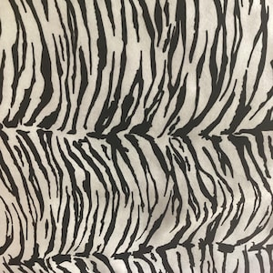 May include: A fabric featuring a high-contrast tiger stripe pattern with bold black lines set against a stark white background. The organic, irregular stripes run vertically across the surface, creating a repeating animal-inspired motif.