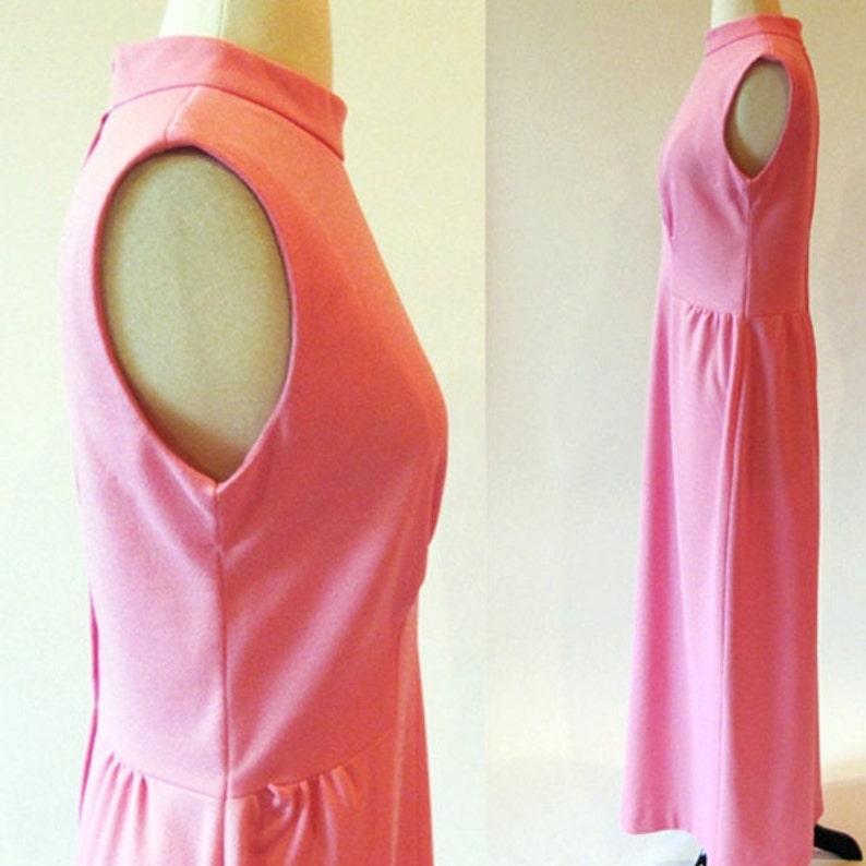 May include: A sleeveless maxi dress in a light pink color. The dress has a high neckline and a simple, fitted silhouette.