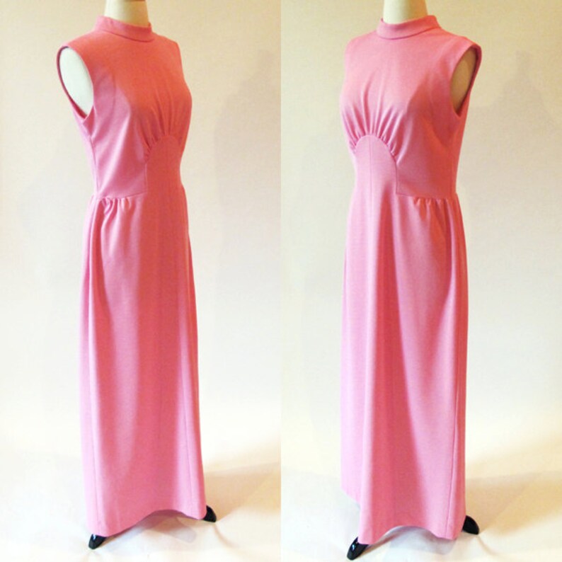 May include: A pink sleeveless maxi dress with a high neck and a fitted bodice. The dress has a gathered detail at the waist and a flowing skirt.