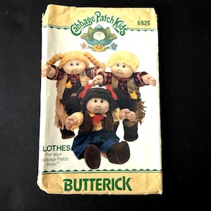 May include: A Butterick sewing pattern envelope for Cabbage Patch Kids clothes, number 6826. The front features three dolls wearing outfits including a fringed vest, plaid shirt, and blue skirt. The text includes Cabbage Patch Kids and Butterick.
