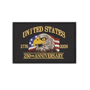 Puede incluir: Parche bordado negro con el texto dorado "UNITED STATES" sobre una cabeza de águila y una bandera estadounidense ondeando. El parche conmemora el 250 aniversario, con los años 1776 y 2026.