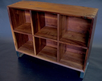 May include: A wooden bookcase with six shelves and metal legs. The bookcase is made of dark wood with a natural finish. The shelves are open and the bookcase is empty.
