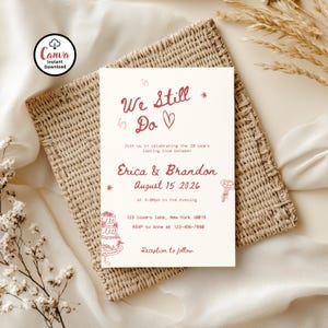 Può includere: Un invito di nozze color crema con il testo "We Still Do" in stile scritto a mano. L'invito include i nomi Erica & Brandon, la data 15 agosto 2026 e le informazioni RSVP. L'invito è su un tappetino intrecciato.