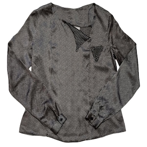 May include: A long-sleeved blouse with a black and white striped pattern. The blouse features a unique asymmetrical neckline with a polka dot accent and a small polka dot pocket. The sleeves have buttoned cuffs.