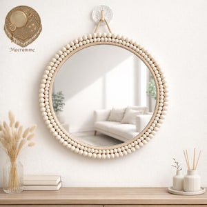May include: Circular wall mirror with a border of wooden beads and a rope hanging loop. The mirror is framed by a cream-coloured bead trim. The word "Macramme" is visible in the upper left corner.