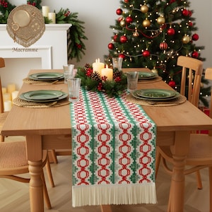 May include: A festive dining table with a patterned table runner in red and green geometric designs. The table is set with green plates, woven placemats, and clear glasses. A Christmas tree with baubles is in the background. The table is made of wood.