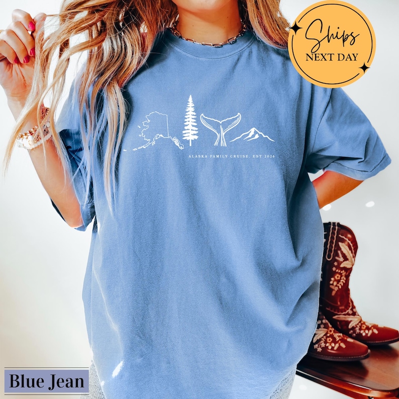 A woman wearing a blue t-shirt with a graphic design of a whale, mountain, and tree, along with the text "Alaska Family Cruise, Est. 2010". She is also wearing a pair of red cowboy boots.