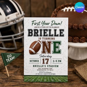 May include: A white rectangular birthday invitation card featuring the text First Year Down! Brielle is turning one, with a brown football graphic, green and brown lettering, and a football field illustration at the bottom with event details.