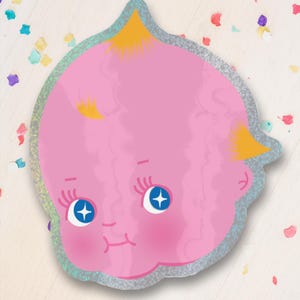 Könnte beinhalten: Ein rosa, gestanzter Aufkleber mit einem Cartoon-Babygesicht mit blauen Augen und gelben Haaren. Der Aufkleber hat einen silbernen Glitzerrahmen und ist von bunten Konfetti umgeben.