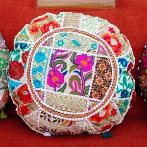Könnte beinhalten: Drei runde, farbenfrohe Zierkissen mit aufwendigen Patchwork-Designs. Jedes Kissen weist eine einzigartige Kombination aus Stoffen, Mustern und Farben auf, darunter Rosa, Grün und Gold. Die Kissen sind mit Perlenkanten und Quasten verziert.