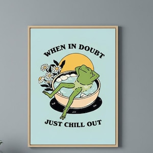 Könnte beinhalten: Ein gerahmter Kunstdruck mit einer Cartoon-Frosch, der sich in einer Wasserschüssel entspannt. Der Frosch ist grün und die Schüssel beige. Der Text lautet "WHEN IN DOUBT JUST CHILL OUT" in schwarzen Buchstaben. Gänseblümchen und eine gelbe Sonne sind ebenfalls im Bild.