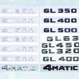 Op de afbeelding: Een verzameling auto-emblemen, waaronder "GL 350", "GL 400", "GL 500", "GL 63", "GL 450", "GL 320" en "4MATIC". De emblemen zijn zilver en zwart, met een glanzende afwerking. De tekst is in een schreefloze lettertype.