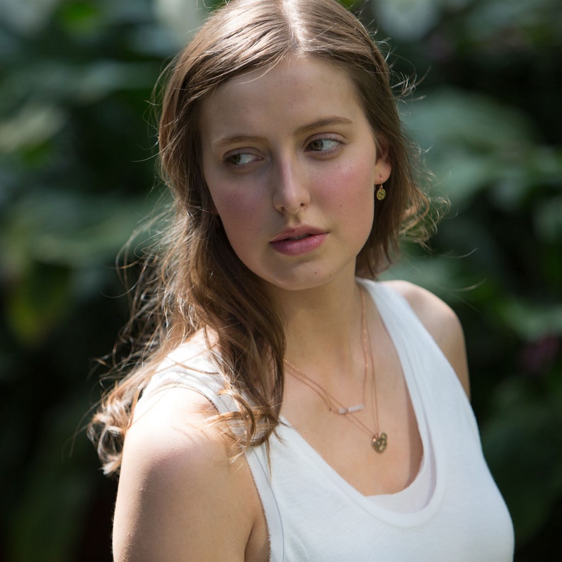 Small gold earrings on model.