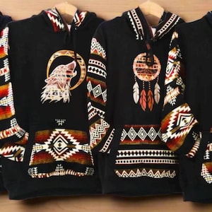May include: Four black hoodies with Native American-inspired designs. Each features a different graphic: a lizard, a howling wolf, a dreamcatcher, and a bear paw. The sleeves and pockets have matching patterned accents.