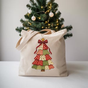 May include: A beige tote bag with a Christmas tree design. The tree is made up of red, green, and white patterned sections, with a gold star and red bow. The bag has a simple design with two handles, perfect for carrying items.