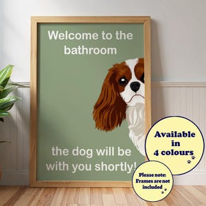 Könnte beinhalten: Ein gerahmter Druck mit hellgrünem Hintergrund und dem Text "Welcome to the bathroom" und "the dog will be with you shortly!". Ein Cavalier King Charles Spaniel schaut hinter dem Text hervor. Der Druck ist in 4 Farben erhältlich.