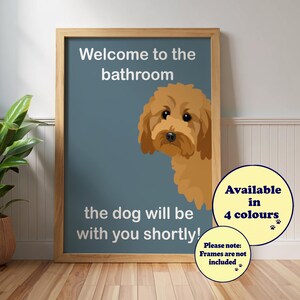 Könnte beinhalten: Gerahmter Druck mit dem Text "Welcome to the bathroom" und "the dog will be with you shortly!" Ein Cartoon-Hund schaut hinter dem Text hervor. Eine kreisförmige Grafik besagt "Available in 4 colours". Der Rahmen ist holzfarben.